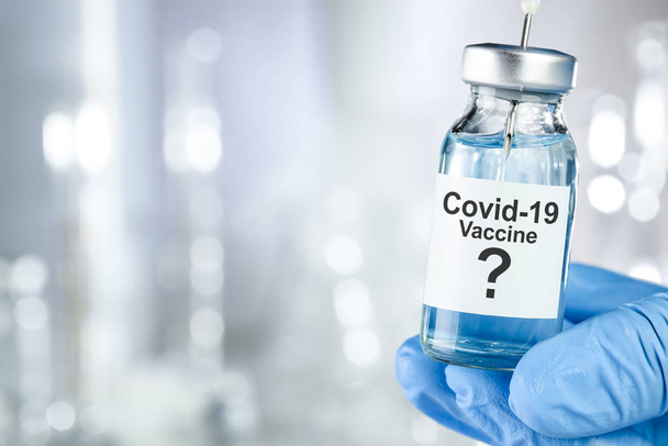Posible concepto de cura con una mano en guantes médicos azules que contienen Coronavirus, virus Covid 19, vial de vacuna
 - Foto, Imagen