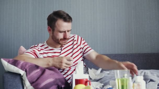 Dorosły chory mężczyzna leży na kanapie i bierze przepisane leki na chorobę.. - Materiał filmowy, wideo