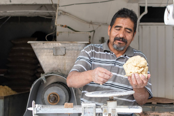 Un uomo che vende pasta nel mulino nixtamal. Per pesare l'impasto viene utilizzata una bilancia a pendolo. - Foto, immagini