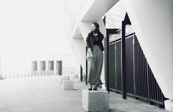 Jong meisje staande plint zoals standbeeld tegen stedelijk landschap - Foto, afbeelding