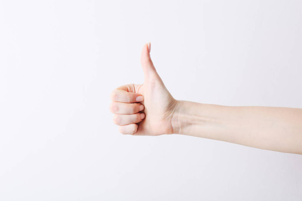 Female hand making gesture like thumb up of right on white background. - Foto, Bild