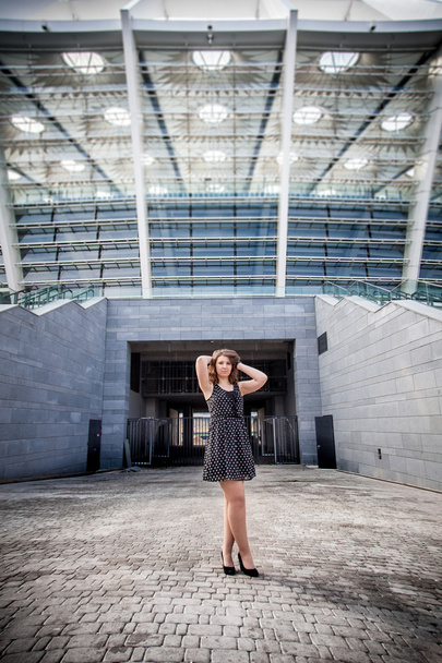 Chica joven posando contra la entrada del estadio grande
 - Foto, Imagen