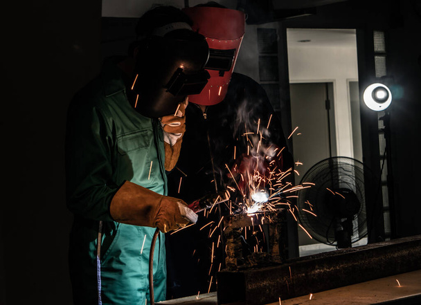The welder is welding the steel with an electric welding machine inside the factory. - Фото, изображение