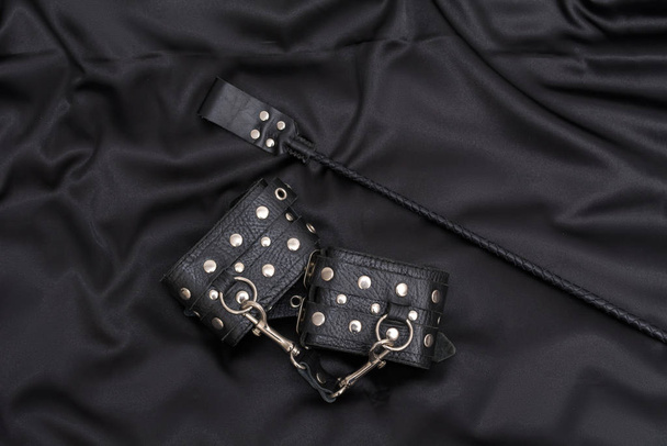 革の手錠と黒の背景にスタック。大人の性的ゲームのためのアクセサリー。BDSM衣装. - 写真・画像