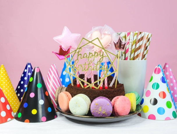 Вкусный торт с мараконами вокруг него с начинкой Happy birthday на столе на розовом фоне. Закрыть
.  - Фото, изображение