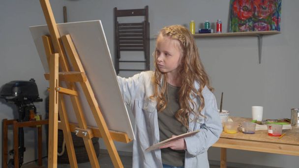 Tyttö emotionaalisesti piirtää kuvan studiossa
 - Valokuva, kuva