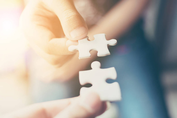 Hand of two people holding jigsaw puzzle connecting together. Concept of partnership and teamwork in business strategy - Photo, Image