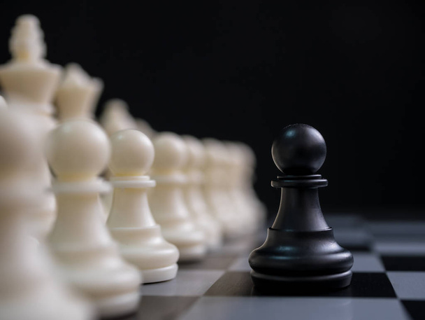 戦略企画ビジネスコンテストのコンセプト。チェスボード上の白いチェスの駒に囲まれた黒い駒 - 写真・画像