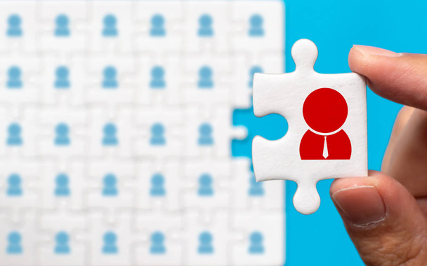 Hand holding piece of white jigsaw puzzle with icon. Human resource management and recruitment business concept - Fotoğraf, Görsel