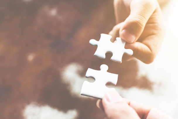 Hand of two people holding jigsaw puzzle connecting together. Concept of partnership and teamwork in business strategy - Foto, Imagen