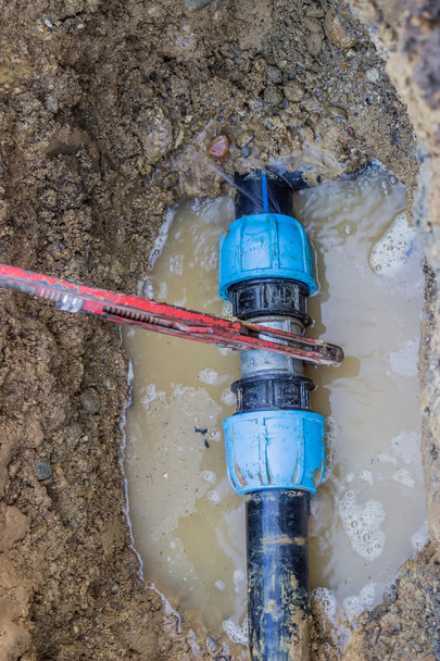 Broken pvc pipe in trench with wrench leaks water 2 - Photo, Image