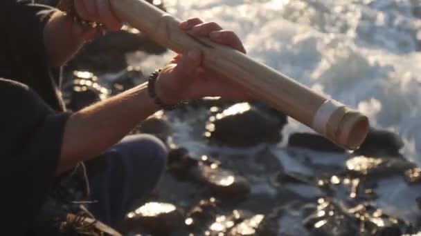 Lähikuva mies pelaa bansuri perinteinen intialainen väline meren rannalla
 - Materiaali, video