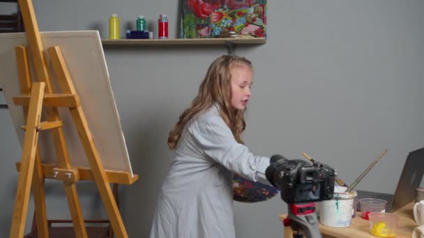 Girl makes a video as she paints a picture - Materiał filmowy, wideo