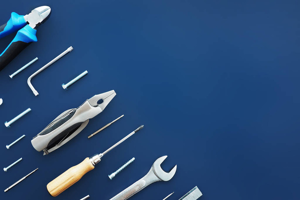 male repair tools: nippers, screwdrivers, keys, bolts, staples for staplers, screws, nuts on a dark blue background - Fotografie, Obrázek