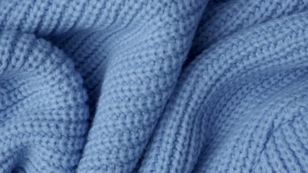 textuur van een warme gezellige gebreide sjaal gevouwen in pittoreske plooien, blauw, bovenaanzicht, selectieve focus, zachte blauwer. - Video