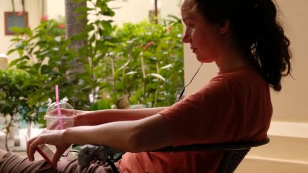 Mujer joven enfocada usando teléfono inteligente en la cafetería
 - Imágenes, Vídeo