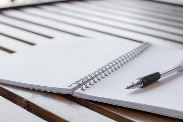 Επιλεκτική εστίαση του στυλό, σημειωματάριο στο ξύλινο τραπέζι με ζεστό φως και αντίγραφο χώρο - Φωτογραφία, εικόνα