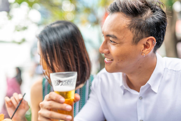 Asiatique jeune couple profiter de plein air temps ensemble boire à une table. - Photo, image