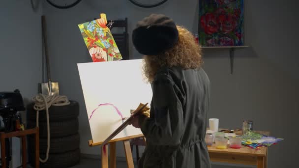 Nainen maalaa kuvan studiossa
 - Materiaali, video