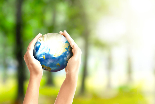 Human hands holding the earth over a green background. Earth day concept - Photo, Image