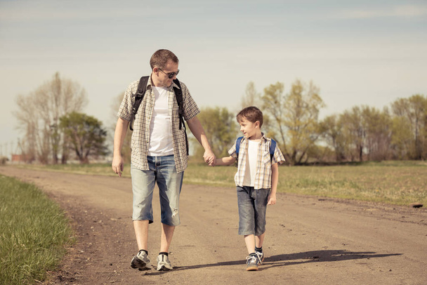 Father and son walking on the road at the day time. People having fun outdoors. Concept of friendly family. - Foto, Imagem