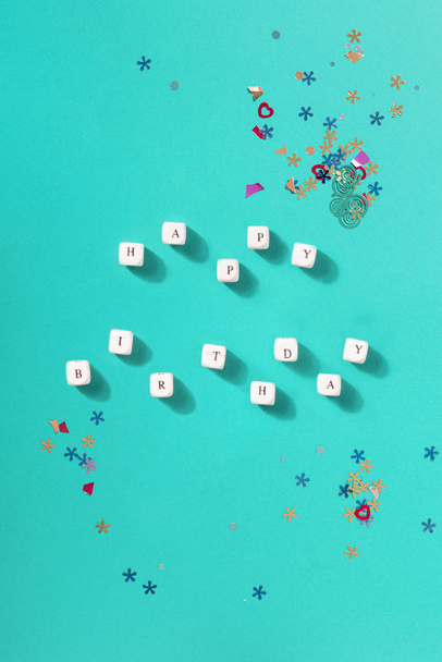 Flat lay happy birthday word with confetti on blue background top view - 写真・画像