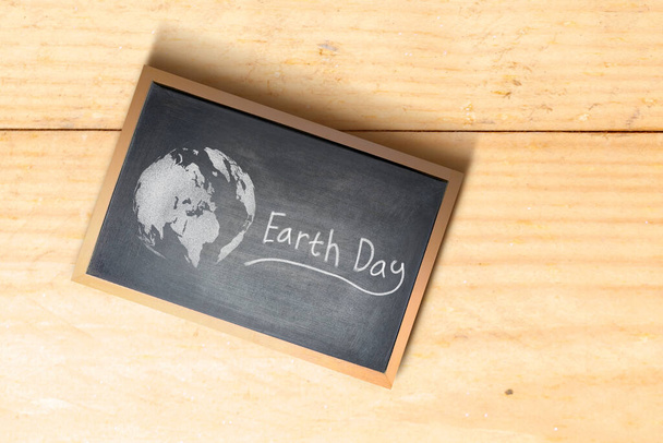 Little blackboard with Earth Day message with wooden table background. Earth day concept - Фото, зображення