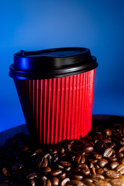 Καφές-to-go Κύπελλο και κόκκους καφέ, σε μπλε φόντο - Φωτογραφία, εικόνα