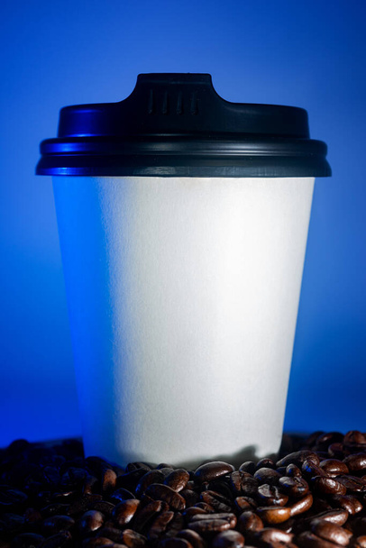 Καφές-to-go Κύπελλο και κόκκους καφέ, σε μπλε φόντο - Φωτογραφία, εικόνα
