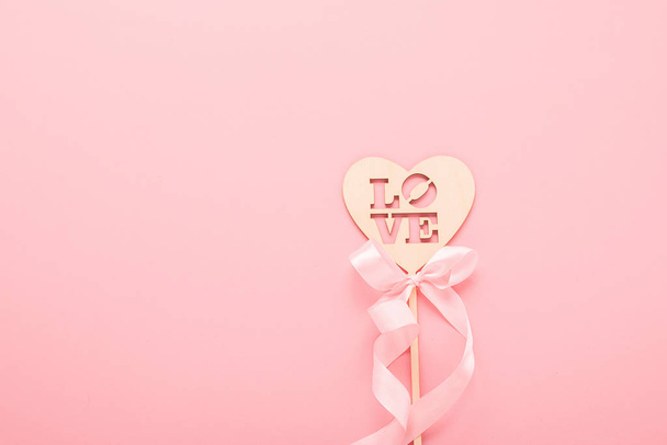 Καρδιά από φυσικά υλικά στηρίγματα φωτογραφιών με αγάπη κείμενο σε ροζ φόντο. Ημέρα του Αγίου Βαλεντίνου έννοια του γάμου. - Φωτογραφία, εικόνα