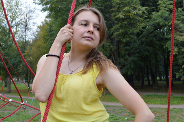 Woman with dark hair in a yellow tank top in a rope park - Photo, Image
