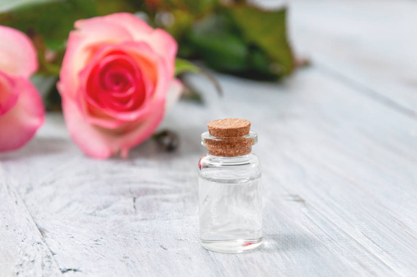 Pink roses, oil bottles and candles on a gray wooden table. March 8. Valentine's Day. Greeting card. Romantic and beautiful background. Spa treatments. Personal care. Love and beauty. - Foto, Imagem