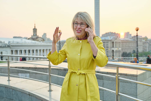 City portrait of mature smiling woman talking on mobile phone - Fotografie, Obrázek