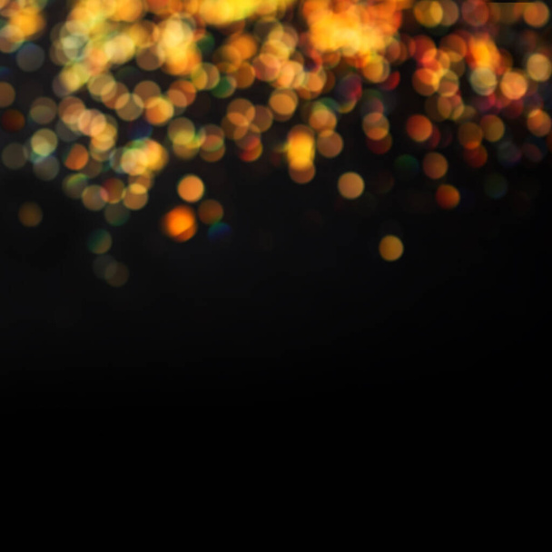 Defocused golden glitter and lights with bokeh effect on black backgroun - Photo, Image
