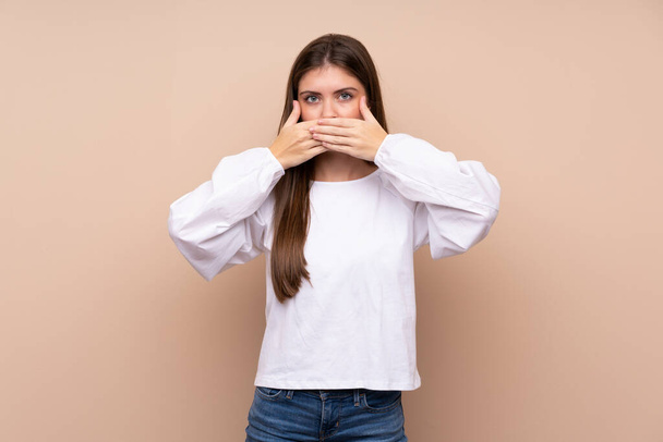 Young girl over isolated background covering mouth with hands - Photo, Image