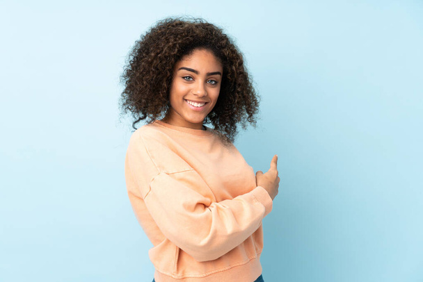 Young African American woman isolated on blue background pointing back - Foto, immagini