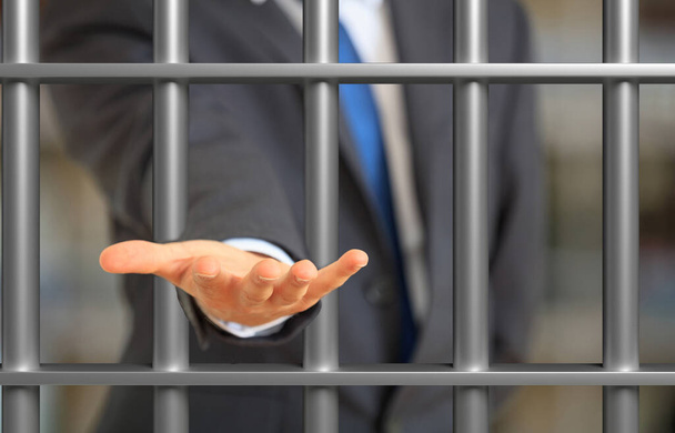 Begging for justice, arrested for bribe concept. Man in suit imprisoned offering an empty palm behind jail bars. 3d illustration - Photo, Image