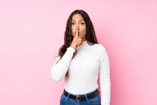 Young woman over isolated pink background showing a sign of silence gesture putting finger in mouth - Photo, Image