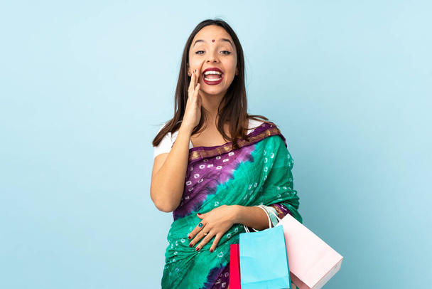 Mujer india joven con bolsas de compras gritando con la boca abierta
 - Foto, imagen
