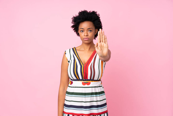 Femme afro-américaine sur fond rose isolé faisant geste d'arrêt
 - Photo, image