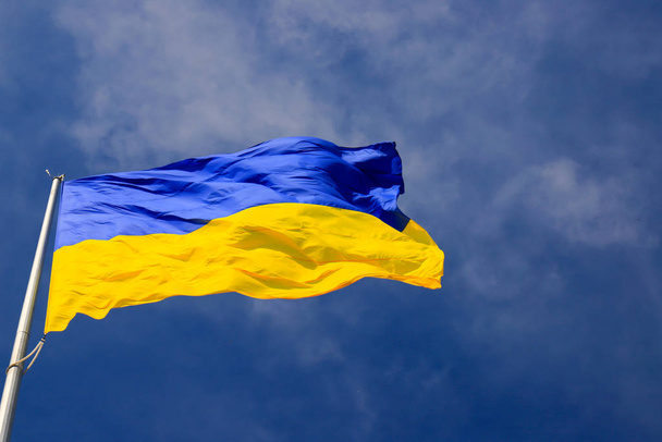 Μεγάλη εθνική σημαία της Ουκρανίας κυματίζει στον γαλάζιο ουρανό. Μεγάλο κίτρινο μπλε ουκρανικό κρατικό πανό στην πόλη Dnepr, Dnepropetrovsk. Ανεξαρτησία, Ημέρα Συντάγματος, Εθνική εορτή, χώρος κειμένου - Φωτογραφία, εικόνα