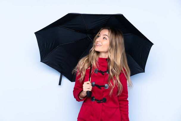 Молода жінка з зимовим пальто і тримає парасольку, дивлячись вгору, посміхаючись
 - Фото, зображення