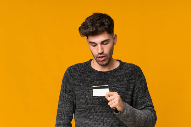 Молодой человек на изолированном фоне держит кредитную карту
 - Фото, изображение