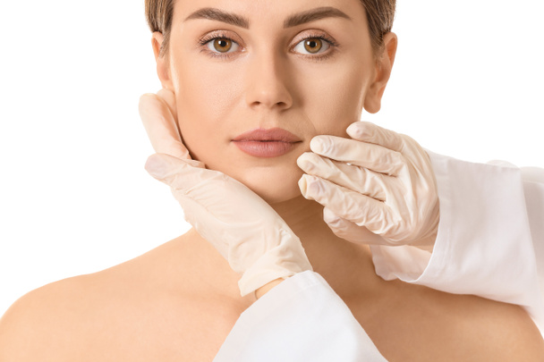 Plastic surgeon touching face of young woman on white background - Photo, Image