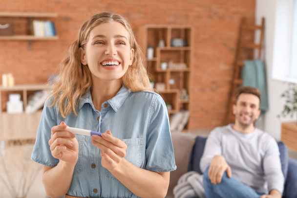 Happy young couple with pregnancy test at home - Foto, immagini