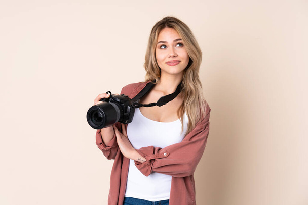 jong fotograaf meisje over geïsoleerde achtergrond op zoek omhoog terwijl glimlachen - Foto, afbeelding