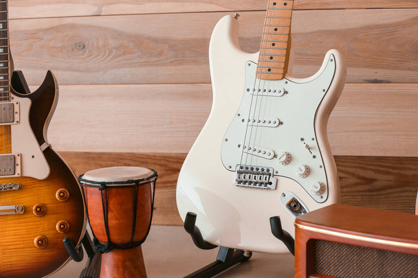 Σύγχρονες κιθάρες, τύμπανο και ραδιόφωνο κοντά σε ξύλινο τοίχο - Φωτογραφία, εικόνα