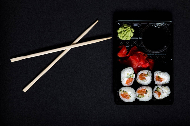 Service de livraison de sushi. Set de sushis en boîte plastique sur fond noir
. - Photo, image