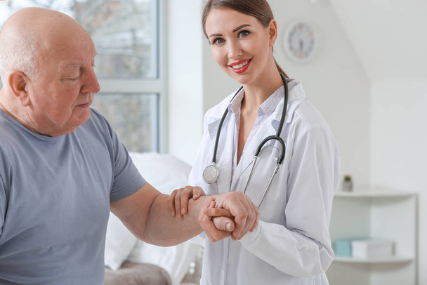 Ženský lékař se starším mužem trpícím Parkinsonovým syndromem na klinice - Fotografie, Obrázek