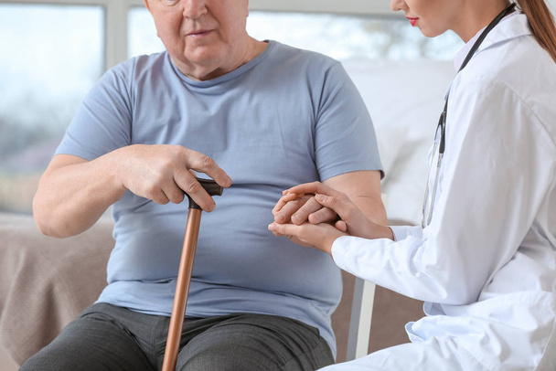 Doctora con un hombre mayor que sufre de síndrome de Parkinson en la clínica
 - Foto, imagen